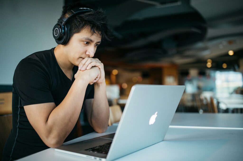 A young man with headphones working at a laptop