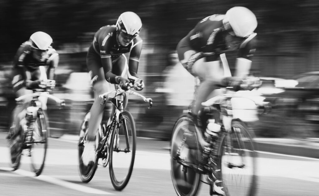 Three road cyclists racing past in a black and white motion blur