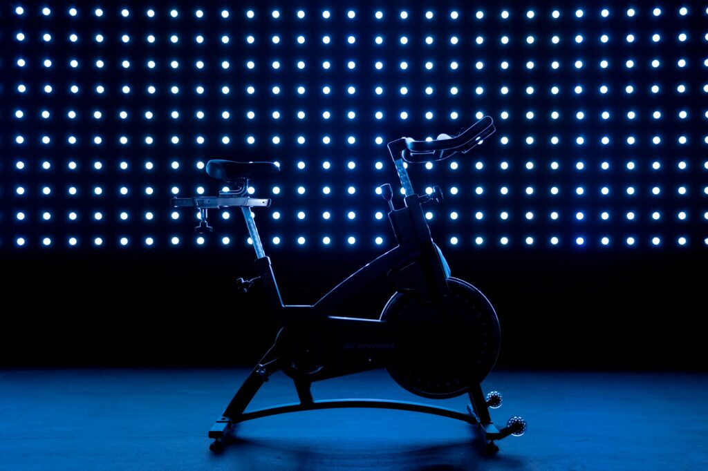 A stationary exercise bike in silhouette in front of a wall of small blue lights